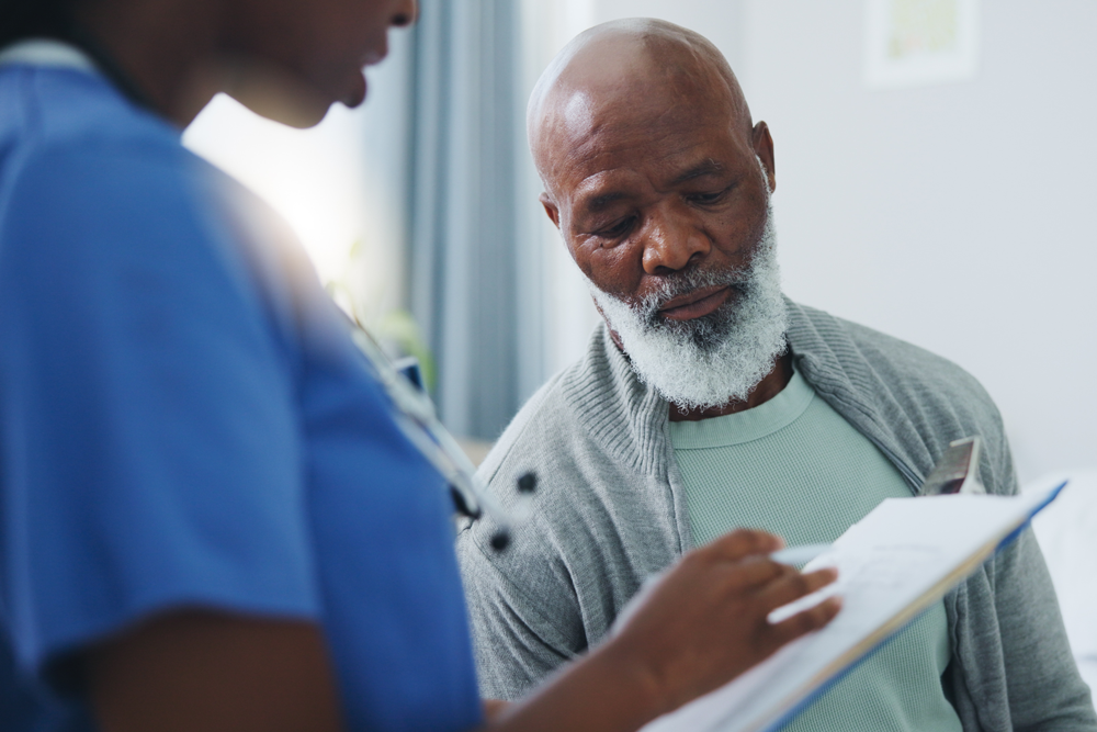 Nurse consulting with a senior male patient and reviewing notes on a clipboard at InterCommunity Health Care.