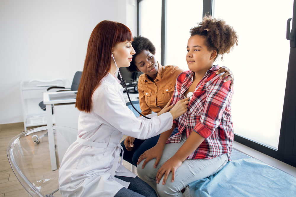 Female pediatrician examining a young girl’s breathing during a checkup at InterCommunity Health Care.
